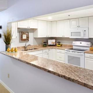 A modern kitchen with white cabinets, a granite countertop, and various appliances.