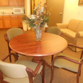 A small meeting room with a round table, four chairs, and a vase centerpiece.