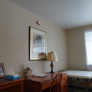 A cozy room with a wooden desk and lamp next to a window.