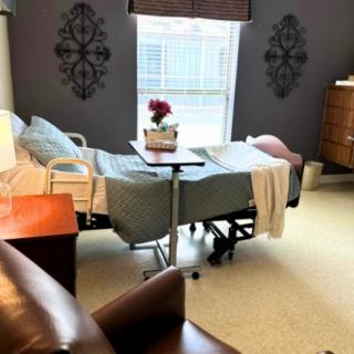 A well-decorated hospital room with a bed and medical equipment near a window.