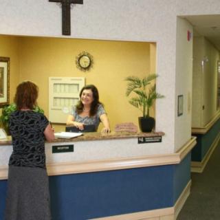 A reception area where a woman is assisting a visitor.
