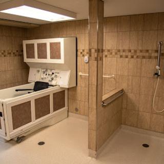 A tiled bathroom with a shower area, sink, and safety handrails.