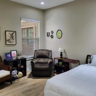 A cozy bedroom with a bed, armchair, and decorative elements.
