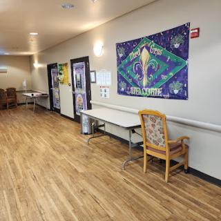 A well-lit hallway featuring decorated walls, with tables and chairs arranged alongside.