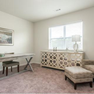 A cozy home office space with a desk, chair, and decorative cabinets.