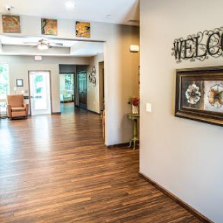A warm and inviting lobby with modern decor and wooden flooring, featuring a welcoming sign.