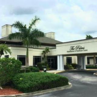 The exterior view of a commercial building featuring lush landscaping and palm trees.