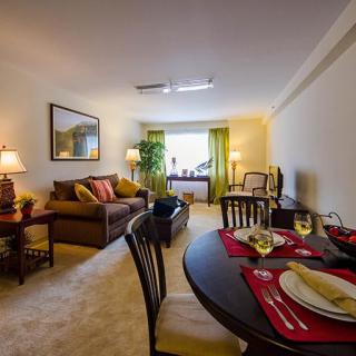 A cozy living room and dining area with elegant decor, featuring a comfortable sofa and a table set for two.