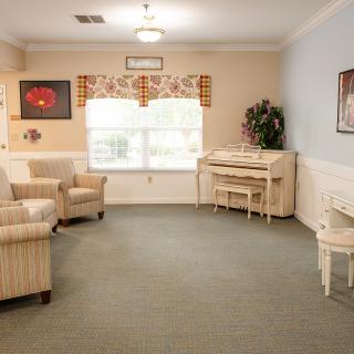 A cozy living room with a piano and comfortable seating.