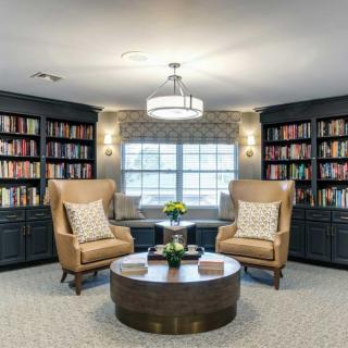 A cozy reading nook with armchairs and bookshelves in a well-lit library.