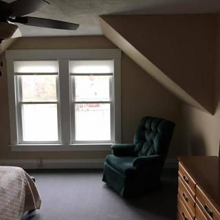 A cozy bedroom with a green armchair near a window, letting in natural light.
