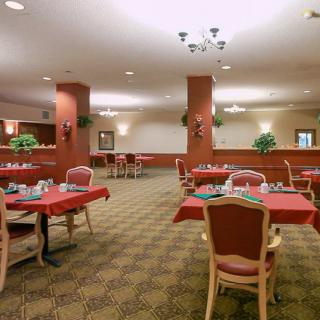 An elegant dining area with tables dressed in red tablecloths and neatly arranged place settings.