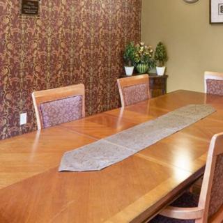 A dining room with a wooden table and chairs, decorated with plants.