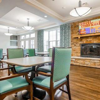 A cozy dining area featuring tables and chairs, a fireplace, and large windows allowing natural light.