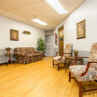 A cozy waiting area featuring a patterned sofa, comfortable chairs, and decorative wall art.