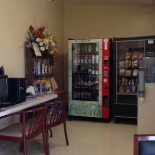 An indoor waiting area featuring vending machines, a computer desk, and chairs.