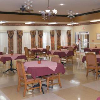 A spacious dining area with neatly arranged tables and chairs, featuring decorative curtains and overhead lighting.