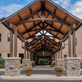 A modern building entrance featuring wooden beams and stone pillars under a clear blue sky.