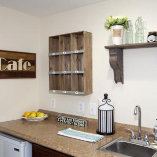 A cozy kitchen corner with rustic shelves, a 'Cafe' sign, and countertop decor.