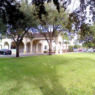 A serene outdoor space featuring a building surrounded by lush greenery and trees.