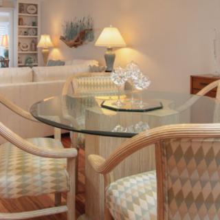 A cozy dining area with a glass table and cushioned chairs, complemented by warm lighting and modern decor.