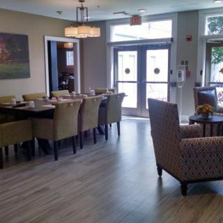 A well-lit dining room with a large table and comfortable chairs arranged around it.