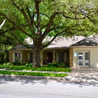 A suburban house with a large tree in the front yard.