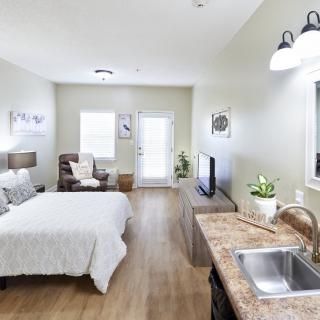 A cozy and minimalist studio apartment featuring a bedroom area and kitchenette.