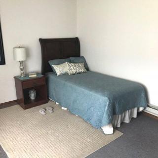 A minimalist bedroom with a single bed, nightstand, and lamp.