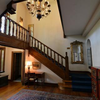 A classic interior featuring a wooden staircase and chandelier.