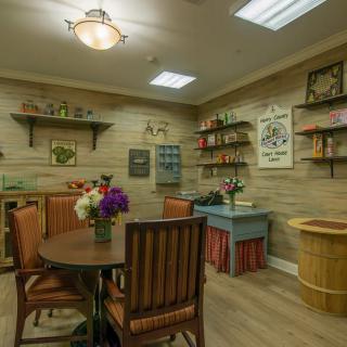 A cozy indoor room with a dining table, wooden walls, and decorative shelves.