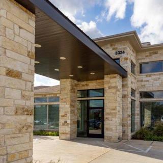 Modern building with a stone facade and large glass windows.