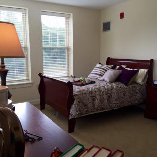 A cozy bedroom with a neatly made bed and a lamp by the window.