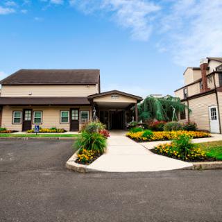 A welcoming entrance with beautifully landscaped gardens and a clear blue sky.
