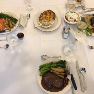 A formal dining setup featuring steak and assorted vegetables.