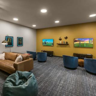 A modern living room with comfortable seating and wall-mounted televisions.