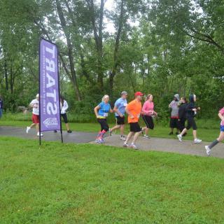 Runners taking off from the start line in a park race event.