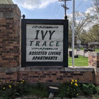 A sign for Ivy Trace Assisted Living Apartments mounted on a brick wall.