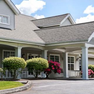 A house with a landscaped entrance featuring shrubs and flowering plants.