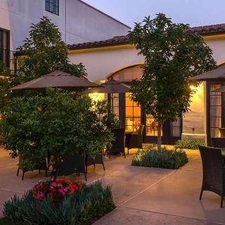 A cozy evening patio with garden furniture, umbrellas, and warm lighting.