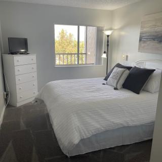 A cozy bedroom with a large bed, white dresser, and a window letting in natural light.