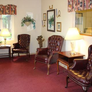A cozy waiting room with leather chairs, lamps, and decorative items.