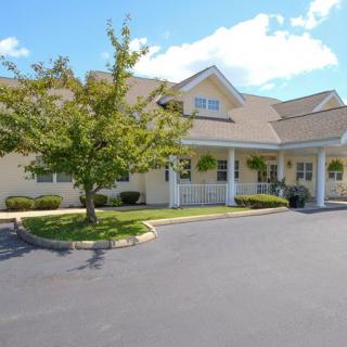 A residential building with a driveway and surrounding landscape.