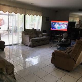 A cozy living room with sofas and a television, featuring glass doors leading outside.