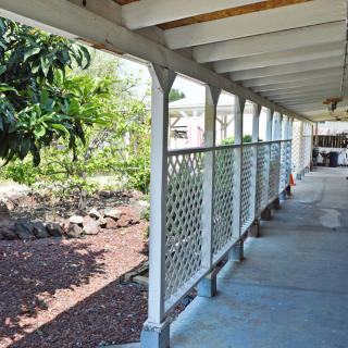 A covered outdoor walkway with a view of a garden area on the left.