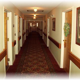 A long, carpeted hallway with doors on either side and overhead lighting.