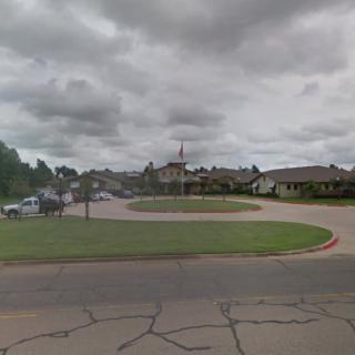 A cloudy day at a suburban road intersection with surrounding buildings.