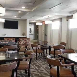 An empty dining area with neatly arranged tables and chairs, featuring modern lighting.
