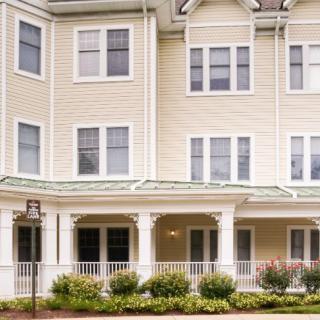 A three-story residential building with a porch and well-maintained landscaping.