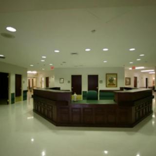 A spacious office lobby with a central wooden reception desk and bright overhead lighting.